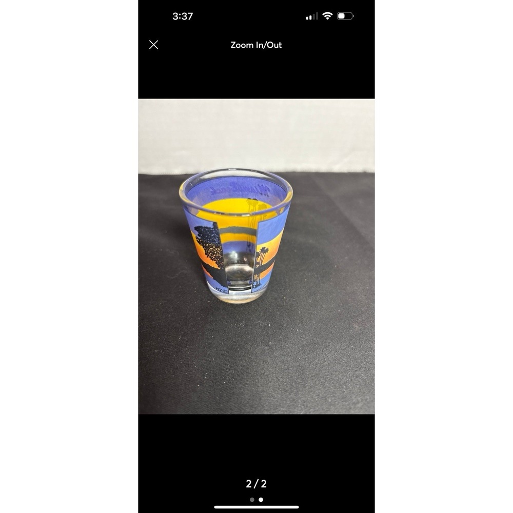 This is a souvenir shot glass featuring a Miami Beach sunset scene with palm tre